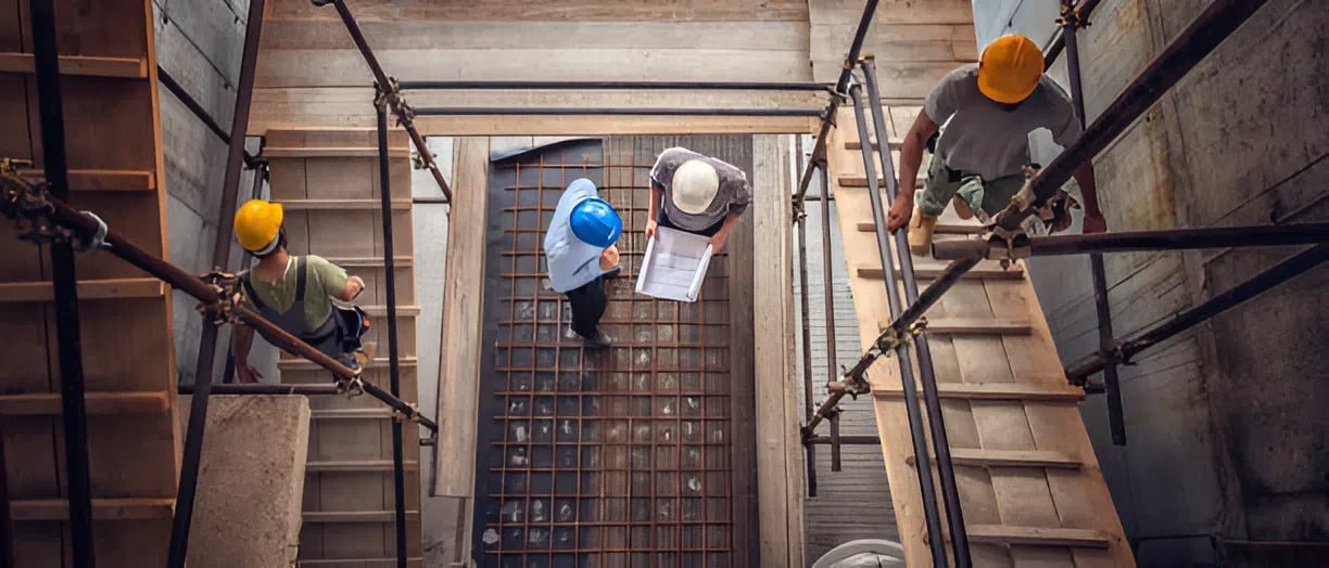 Commercial painting team inspecting scaffolding and structural surface during commercial building restoration and maintenance project